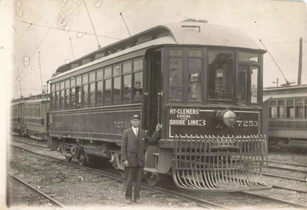 Vintage streetcar with conductor standing.