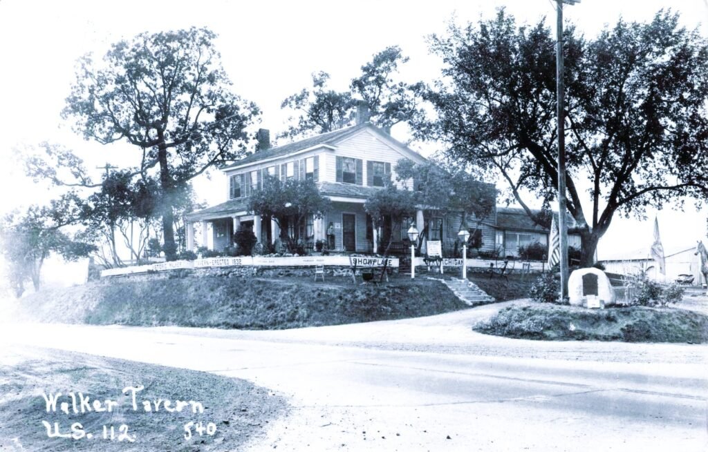 “Walker Tavern U.S. 112.” The image shows the tavern set above the road, with signage that reflects its roadside tourism years.