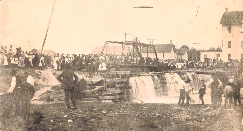 Historic crowd near a waterfall.