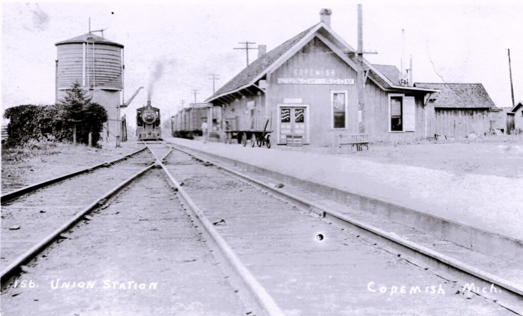 Copemish Union Station and water tank postcard view—water and steam were part of keeping trains moving through town.