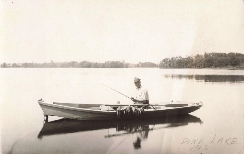 Man fishing in a calm lake. - History of Fenton Michigan