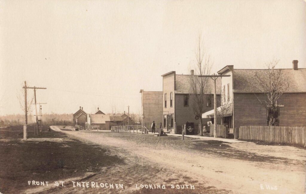 A dirt main street in early Interlochen, showing a working town with small businesses close to the rail era. 