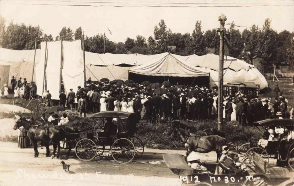 A large crowd gathers under canvas tents for a revival meeting in 1912. These events brought together residents from across the area, blending religion, community, and social life.