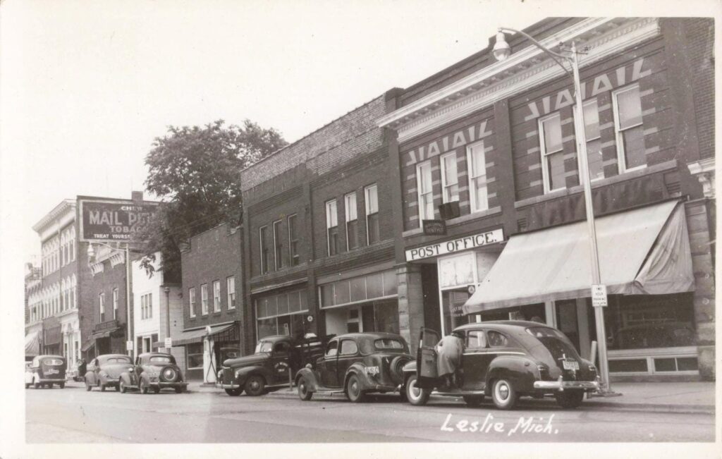 1930s downtown Leslie Michigan with parked automobiles and brick commercial buildings