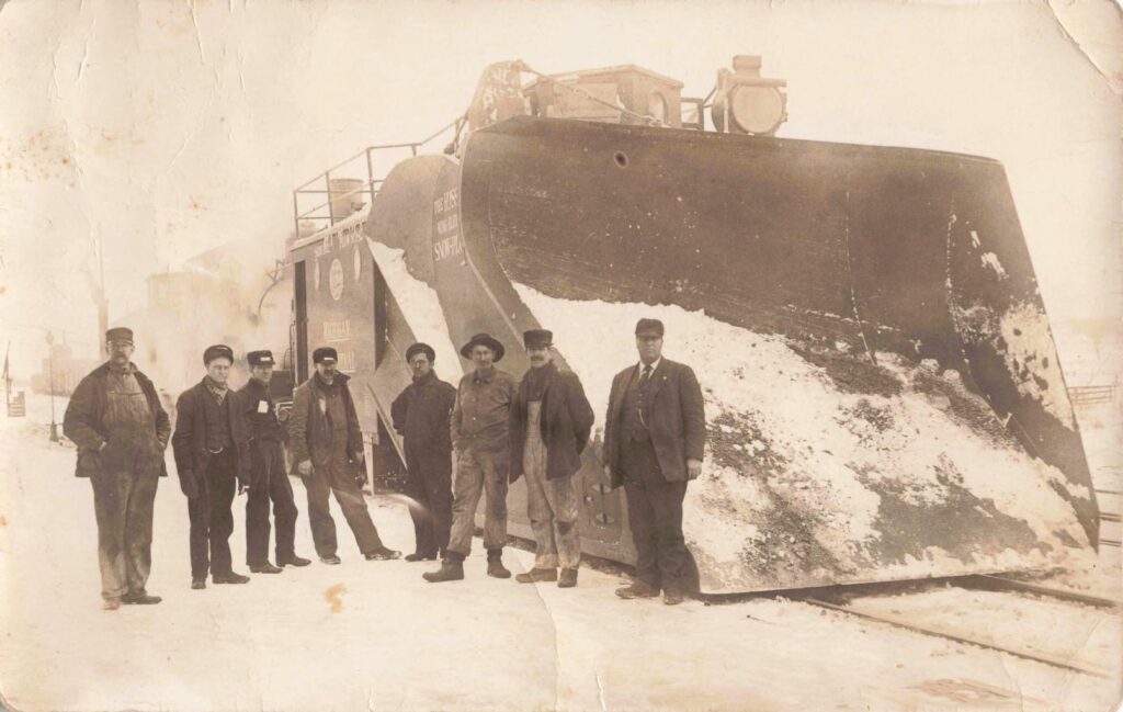 Men standing by a snowplow train.