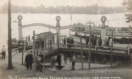 Black-and-white postcard photo of people boarding a two-deck passenger boat at the Park Island landing on Lake Orion, with docks and railings in the foreground.