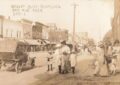 Early 1910s downtown Bad Axe Michigan showing dirt streets, wooden storefronts, wagons, horses, and early automobiles.