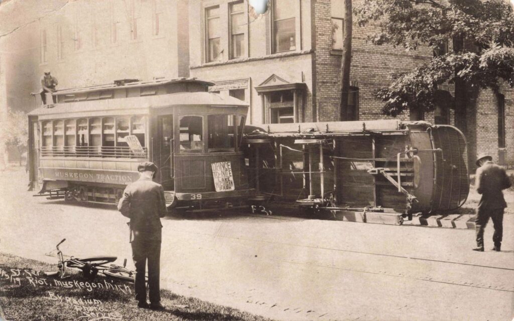 Overturned Muskegon Traction streetcar beside city buildings during the 1919 fare riots.