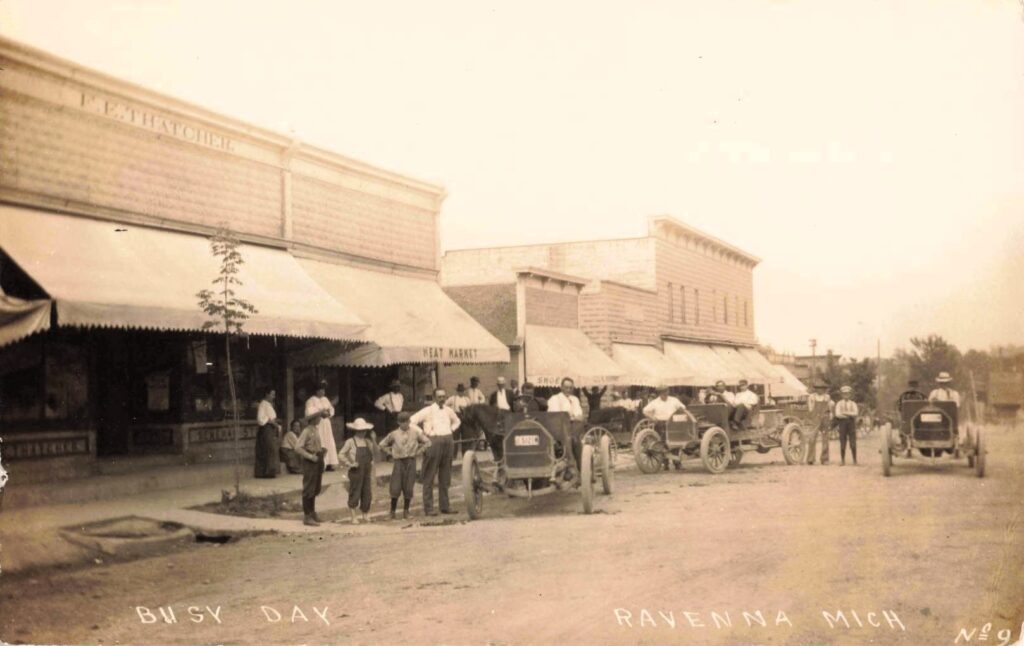 Busy day Ravenna Michigan early cars storefronts people Muskegon County history