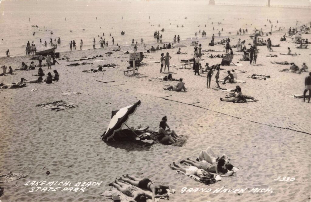 Crowded beach with sunbathers and umbrellas.