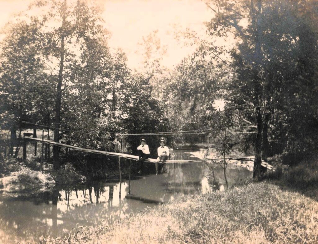 Boys seated near a narrow bridge at Lake Ann, showing everyday recreation near the water.