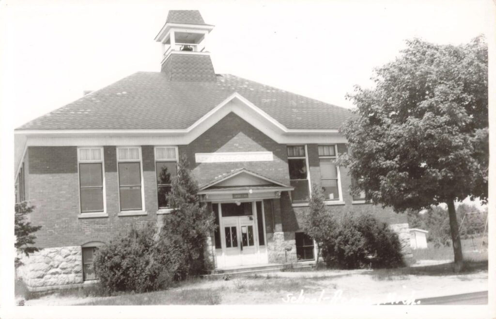 Stanford School shows a later and more formal school building, with brick walls, tall windows and a bell tower.