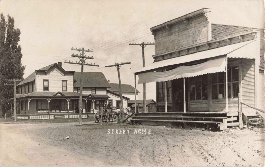 The history of Acme Michigan includes a dirt street, storefront, horse team and utility poles show Acme moving from rural village life into the modern age.