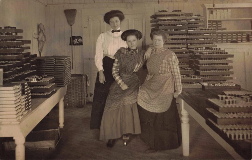 Interior workroom with three women and rows of spools.