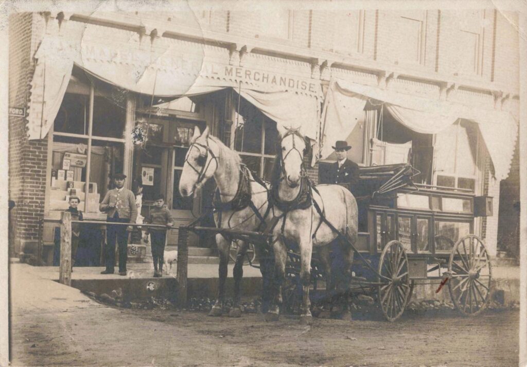 Historic horse-drawn carriage outside store.