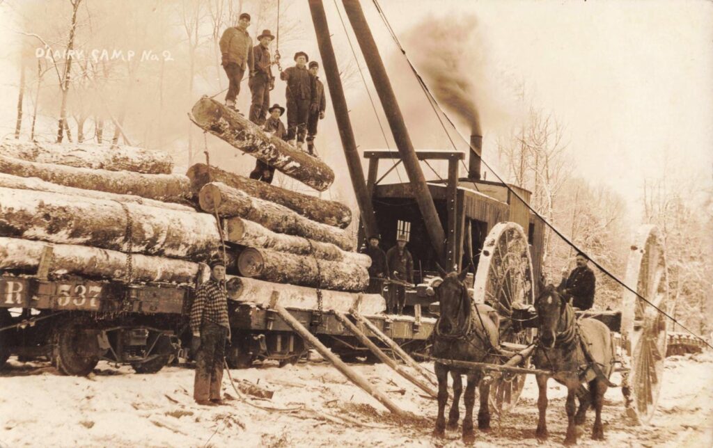 0
O’Lairy Camp No. 2, near Sigma: Workers, horses, rail cars and a steam engine crowd the camp yard, showing the scale and organization of timber work east of Sigma.