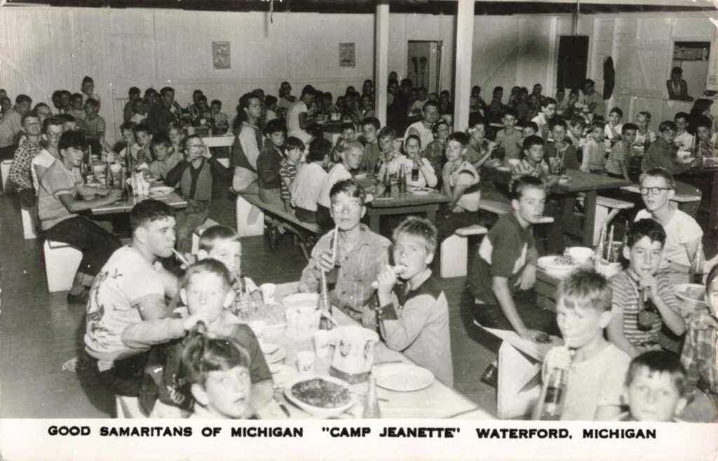A crowded dining hall shows the camp’s scale and the daily routine of meals served to large groups of boys.