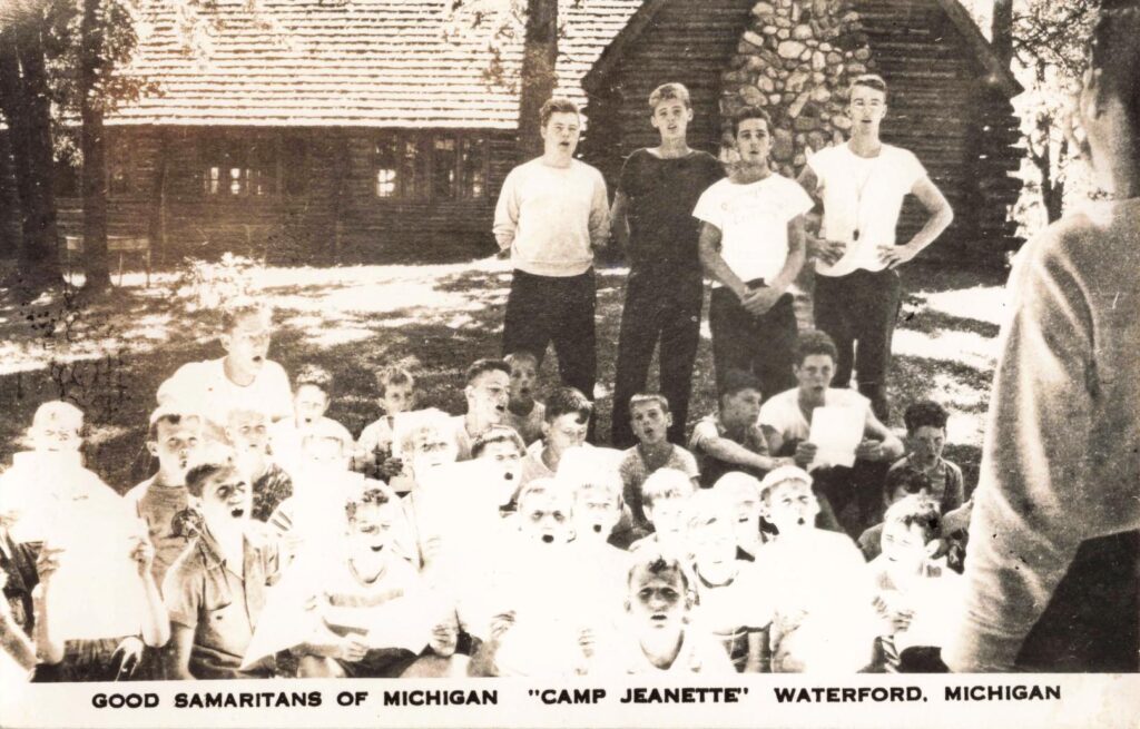 Boys assembled outside a rustic building suggest the group structure and camp routines used at Camp Jeanette.