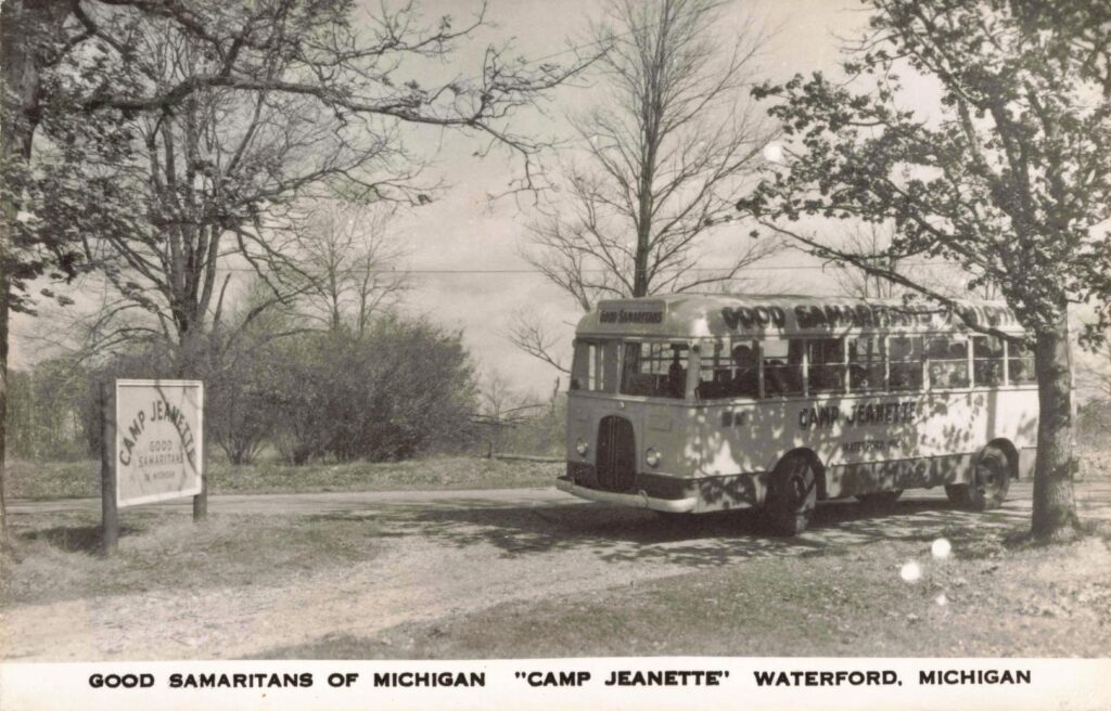 The Camp Jeanette bus arrives near the camp sign, linking Detroit charity work with Waterford’s lake country.