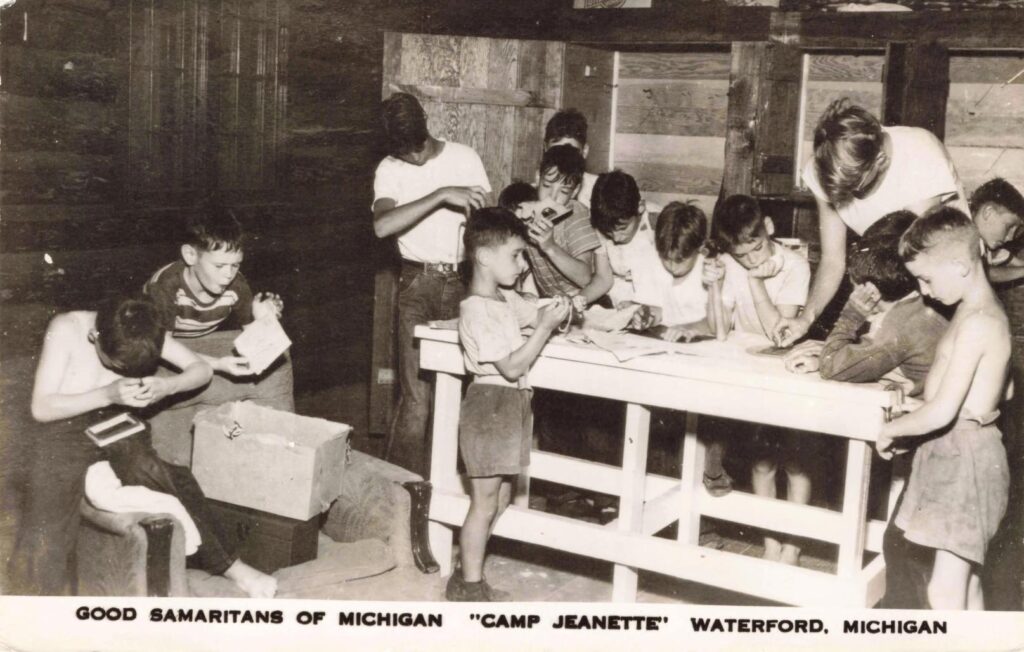 Boys gather around a worktable inside Camp Jeanette, showing the camp’s mix of supervision, craft work and group activity.