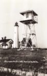 Black-and-white photo of Sturgeon Point Lighthouse, a keeper’s house and a tall wooden or metal lookout tower near Harrisville, Michigan.