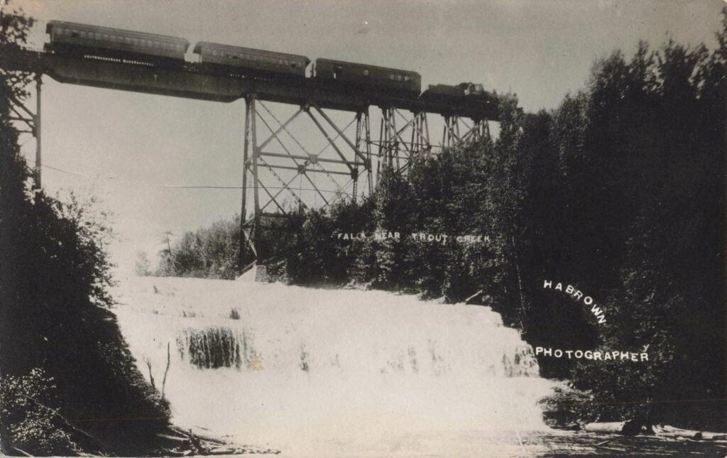 Steam train crossing a tall railroad bridge near Trout Creek Michigan.
