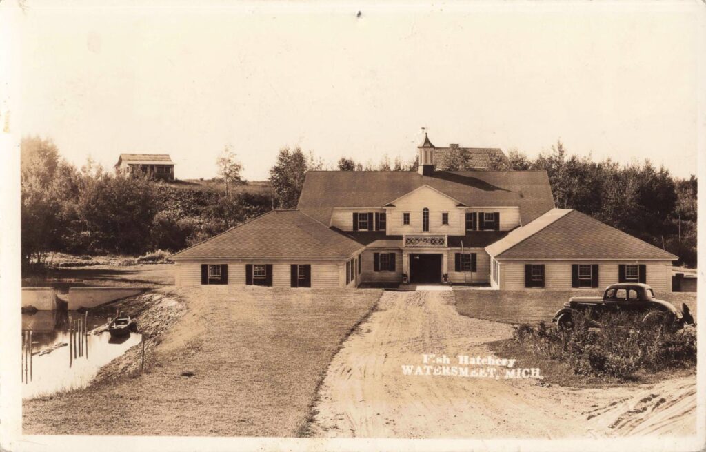 Watersmeet Michigan Fish Hatchery in 1935 beside water and trees.