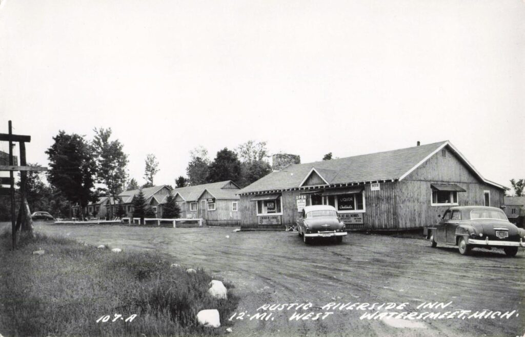 Rustic Riverside Inn west of Watersmeet Michigan with cars and roadside buildings.