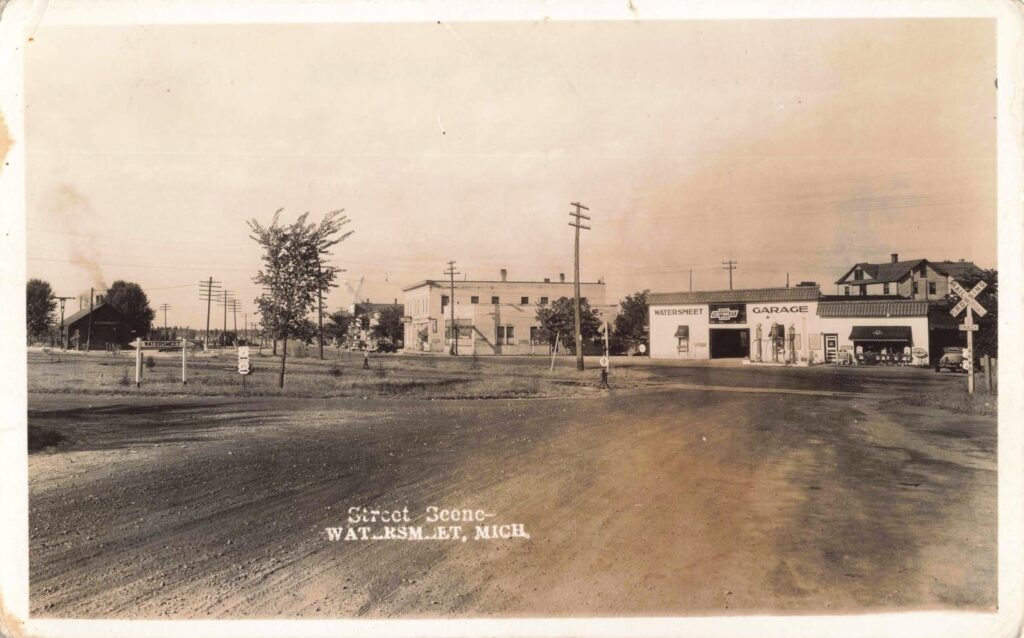 Watersmeet Michigan street scene in 1935 with railroad tracks and cars.