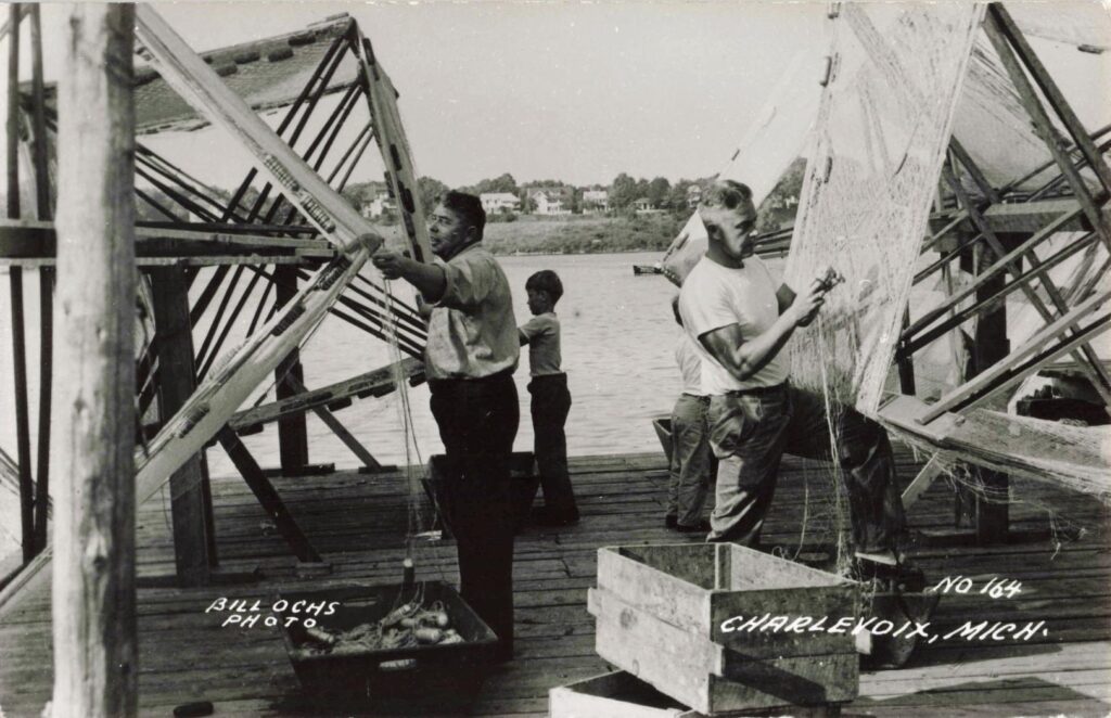 Men repairing fishing nets by water