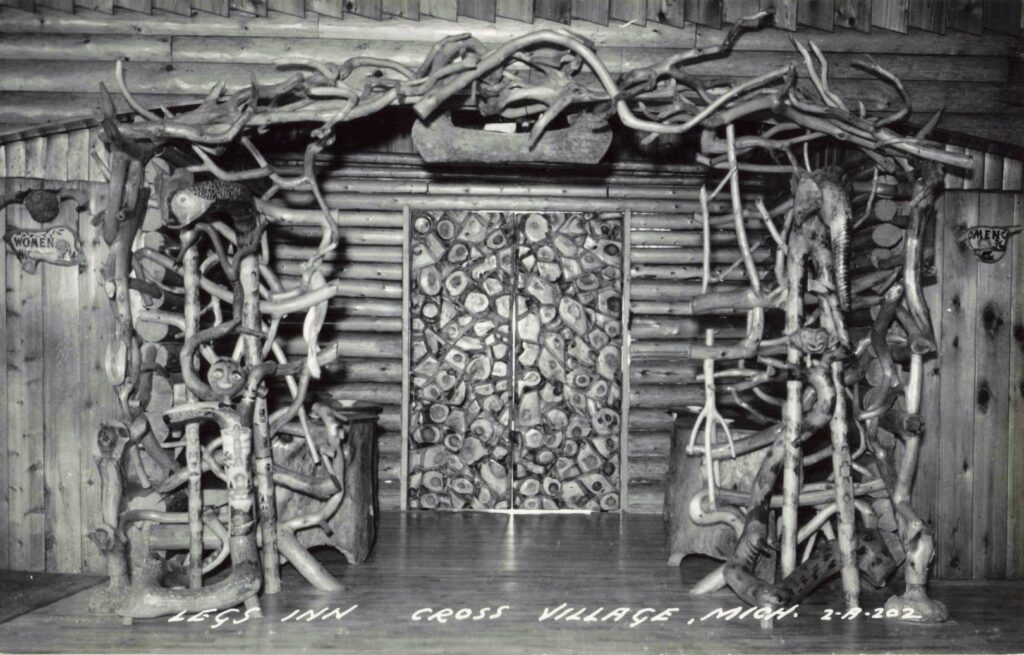 Historic interior postcard of Legs Inn in Cross Village, Michigan, showing rustic carved wood, branchwork and decorative folk-art details.