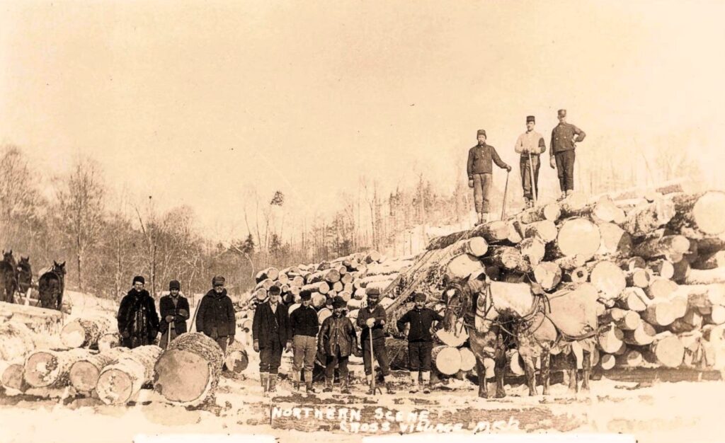 Historic logging scene near Cross Village, Michigan, with workers, horses and large stacks of cut timber.