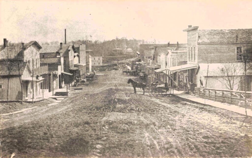 Washington Street during the horse-and-buggy era, with dirt roads, boardwalks and merchants serving surrounding farms.