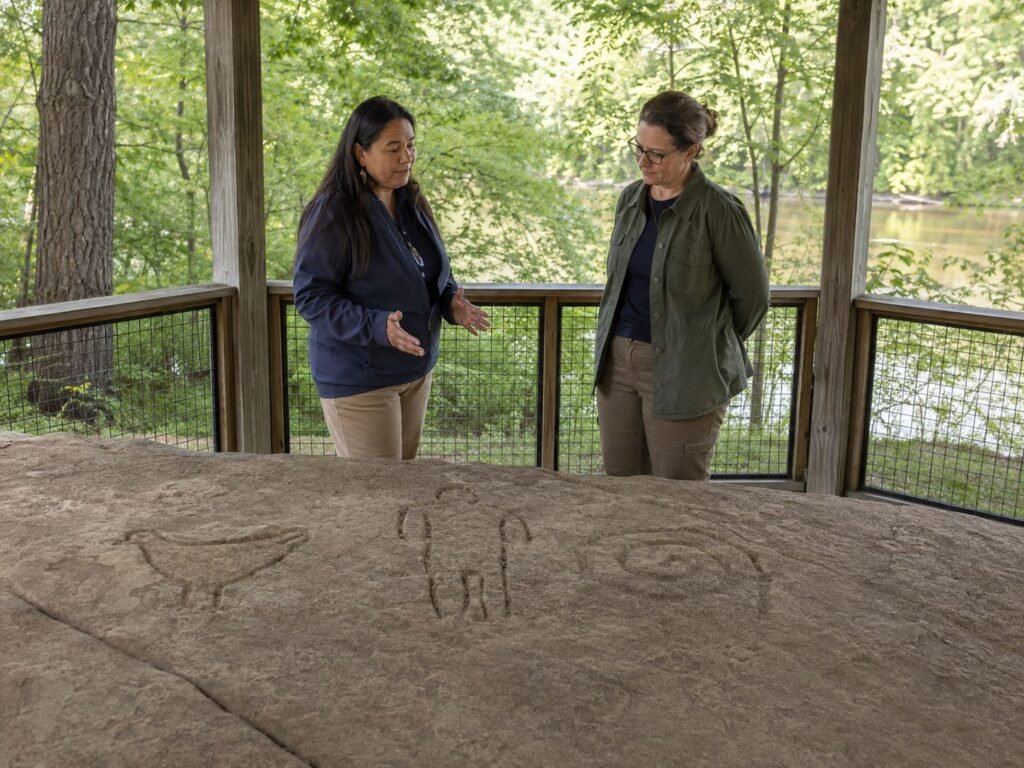 Two women discussing rock carvings outdoors.