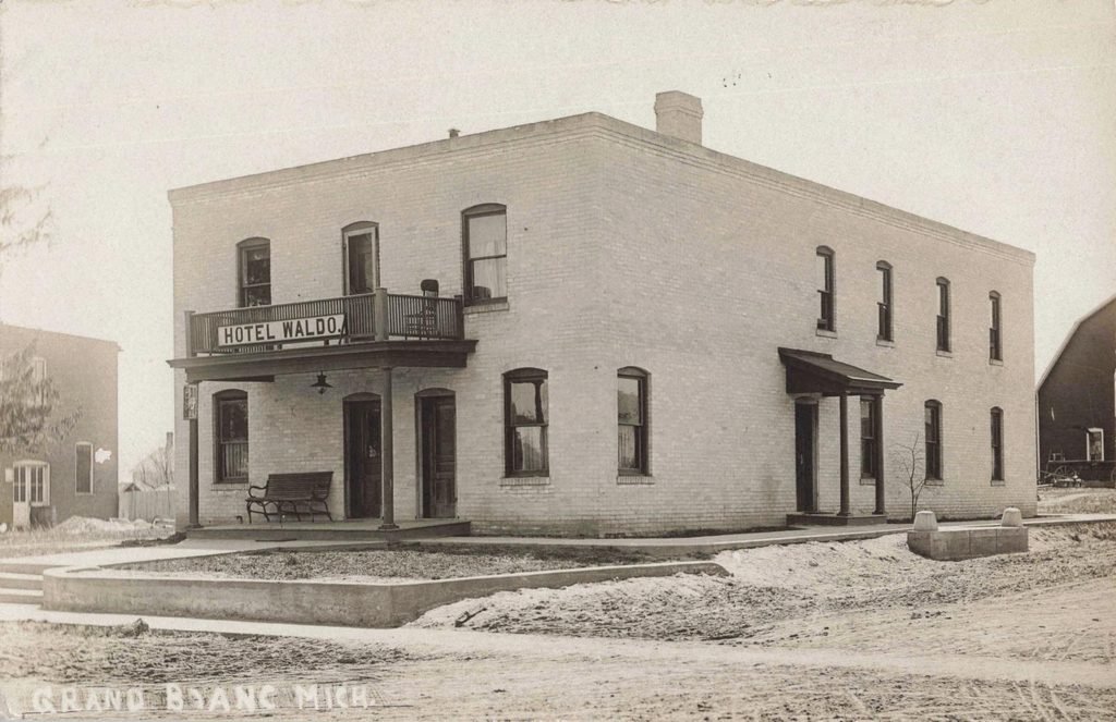 Hotel Waldo in Grand Blanc, a two-story lodging business with a balcony above its entrance