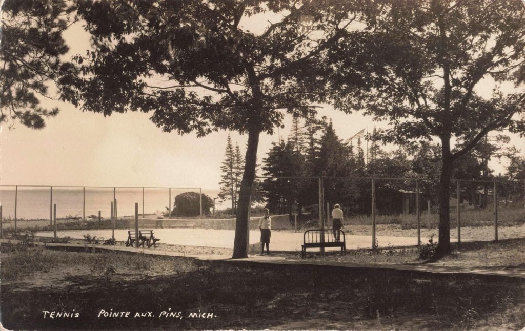 Historic postcard showing two people at a tennis court beside Lake Huron at Pointe Aux Pins, Michigan.
