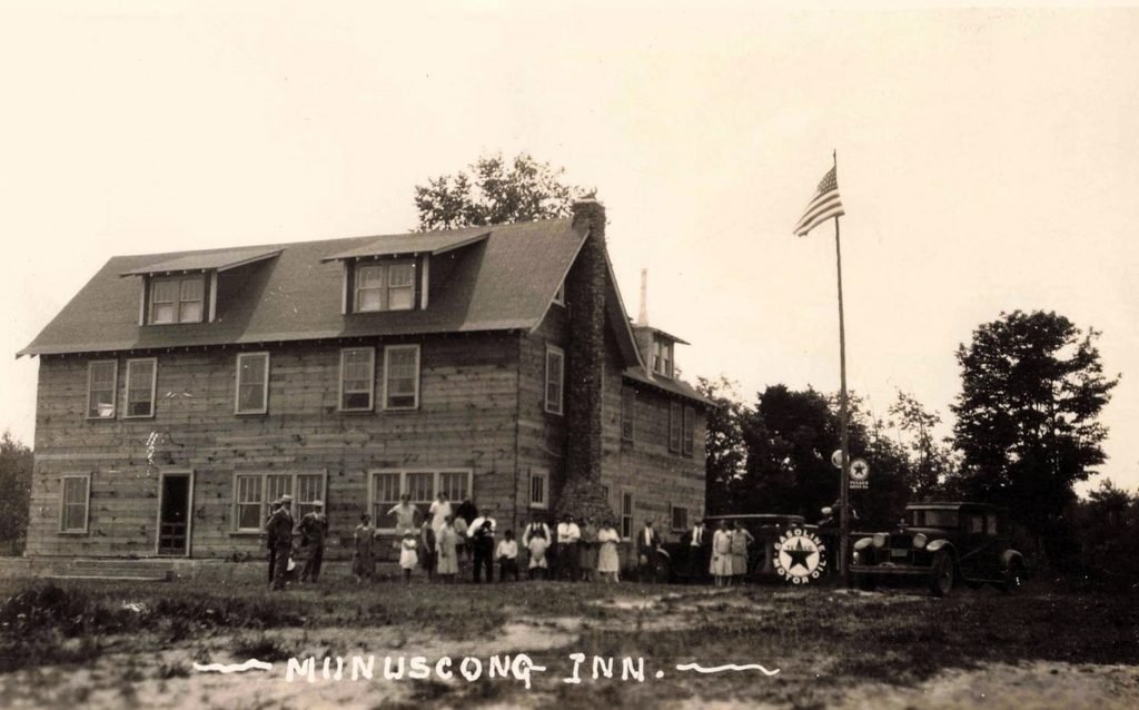A related exterior view shows adults and children beside the lodge, early automobiles and gasoline signs. The group and exact date remain unidentified. Source: supplied postcard; creator and exact date unconfirmed.