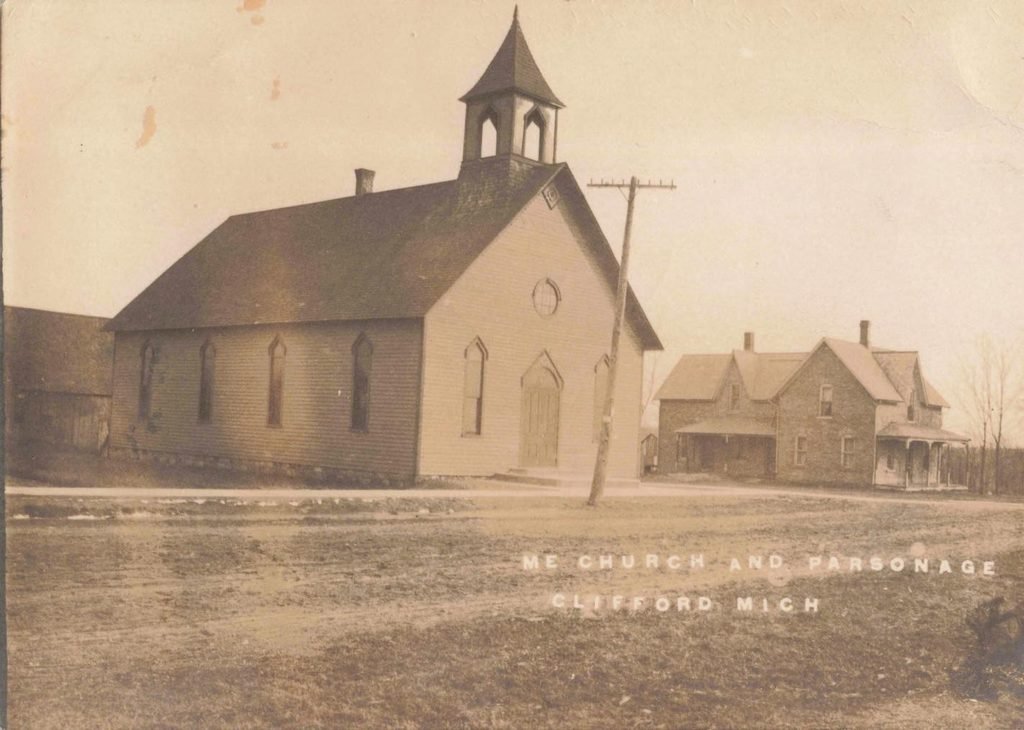 Historic Methodist Episcopal Church and parsonage in Clifford Michigan with a bell tower and neighboring residence.