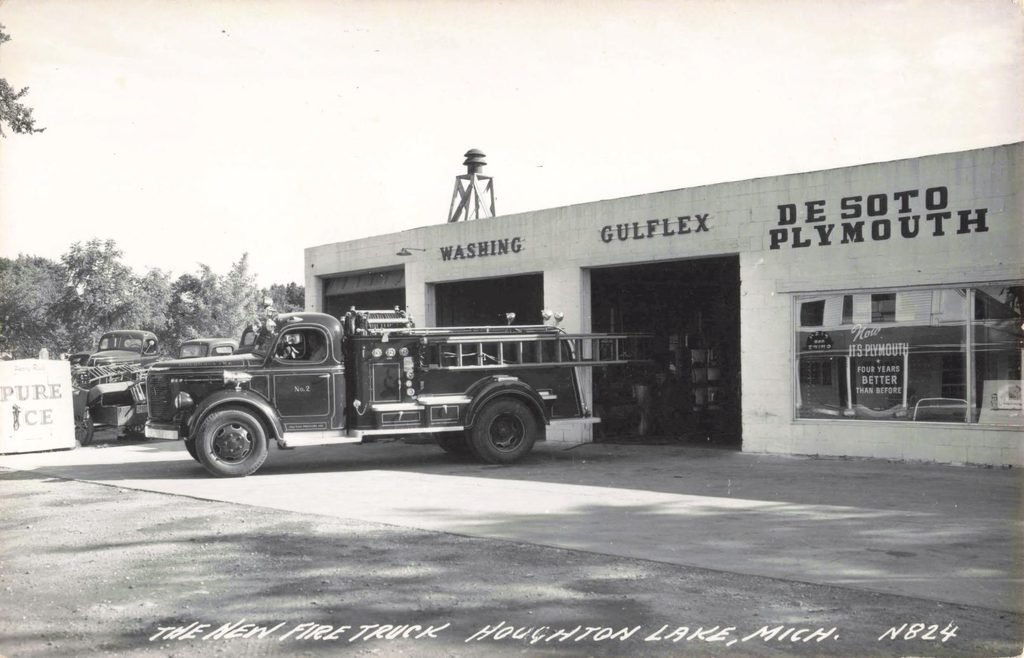 Historic Houghton Lake Michigan fire truck outside DeSoto Plymouth automobile dealership