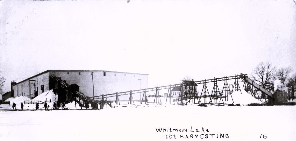 History of Whitmore Lake Michigan - Historic postcard showing an industrial ice-harvesting operation on frozen Whitmore Lake, with wooden equipment and large structures